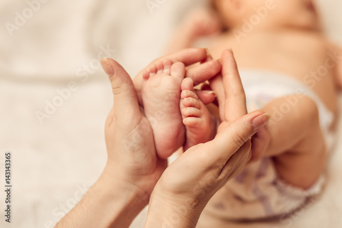 Mother holding tiny foot of newborn baby photo