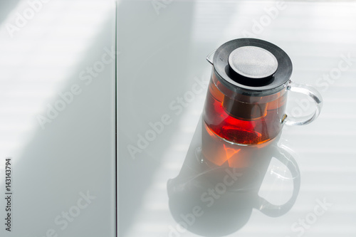 Transparent teapot on the white table. Natural light from the window.