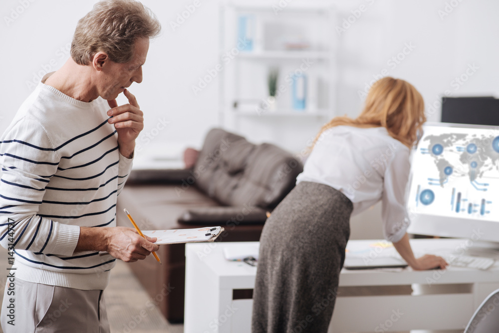 Freaky aged manager looking at young coworker back at workplace Freaky aged manager looking at young coworker back at workplace