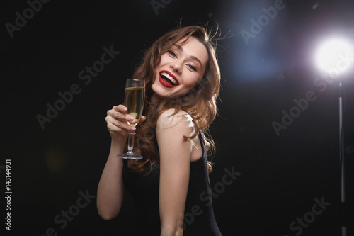 Smiling young woman with red lips holding glass of champagne