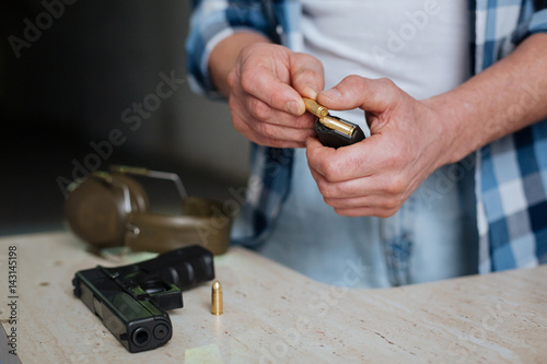 Nice pleasant man putting a bullet into the cartridge clip