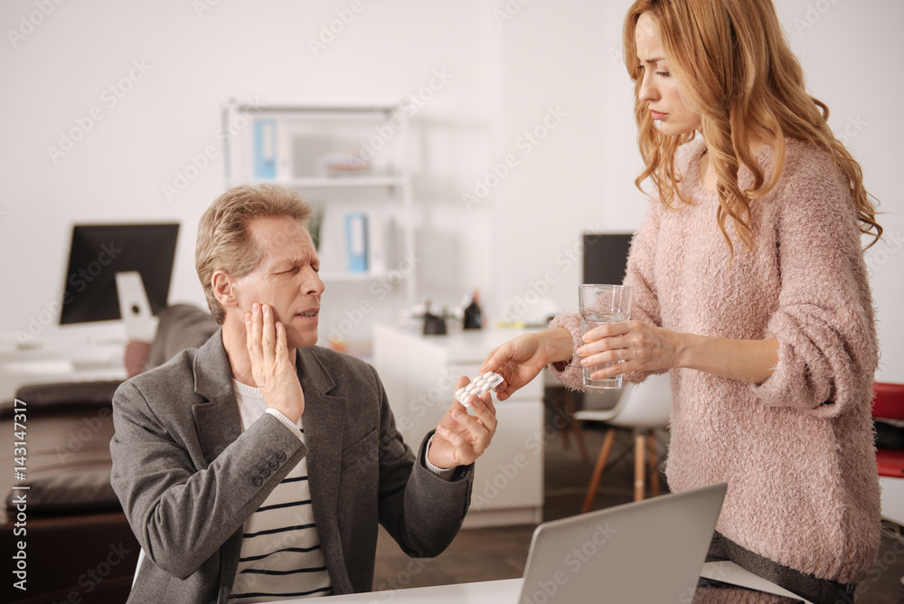 Concerned secretary offering pills to ill boss in the office Concerned secretary offering pills to ill boss in the office