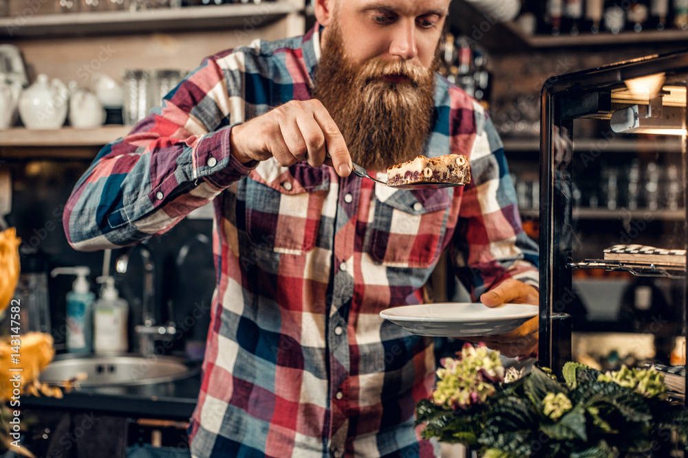 A man holds chocolate cake at the counter in the bakery shop.