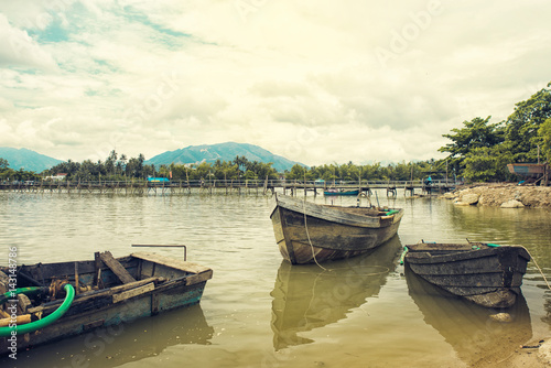 Fototapeta Naklejka Na Ścianę i Meble -  Fishing wooden boat on a river. Boat on a river in Vietnam. Old bridge on background. Toned photo