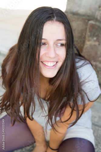 beautiful girl with long hair sitting on the street happy and smiling