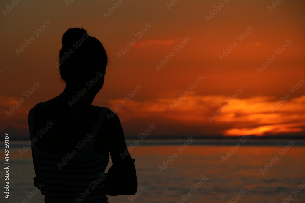 Lady during Sunset / Young Lady enjoys the beautiful sunset at the beach of the Indian Ocean, Mauritius, Africa.