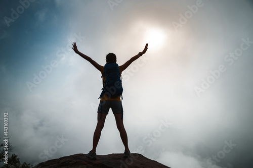 cheering young woman backpacker enjoy the view on sunrise mountain peak