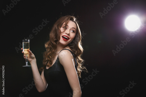Happy lovely woman with glass of champagne standing and smiling © Drobot Dean