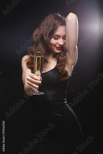 Smiling sensual woman with glass of champagne standing and posing
