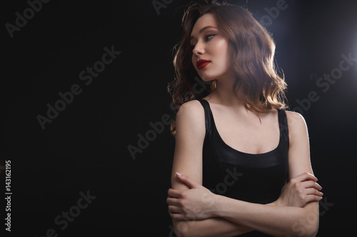 Gorgeous young woman standing with arms crossed and looking away