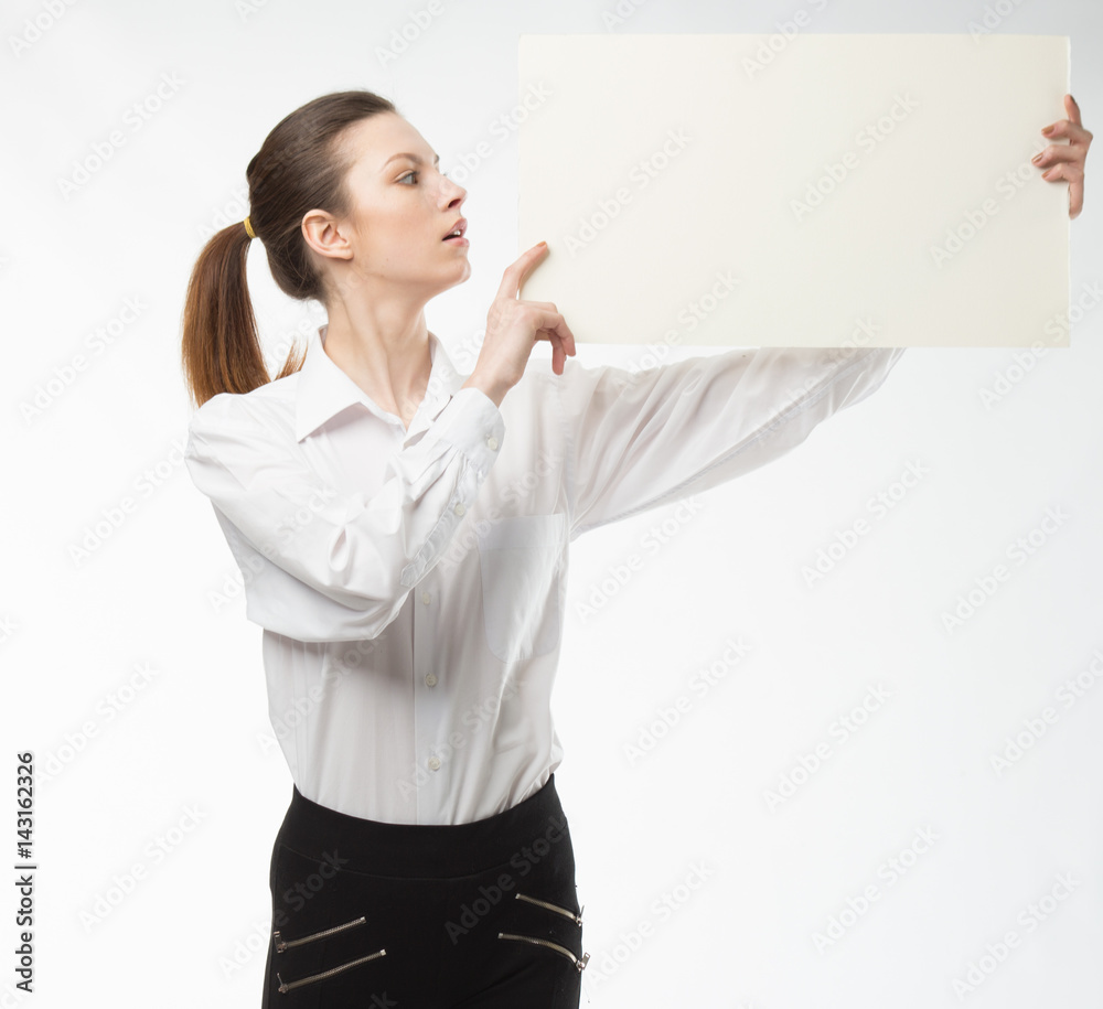 Young happy woman showing presentation, pointing on placard over gray background Young happy woman showing presentation, pointing on placard over gray background