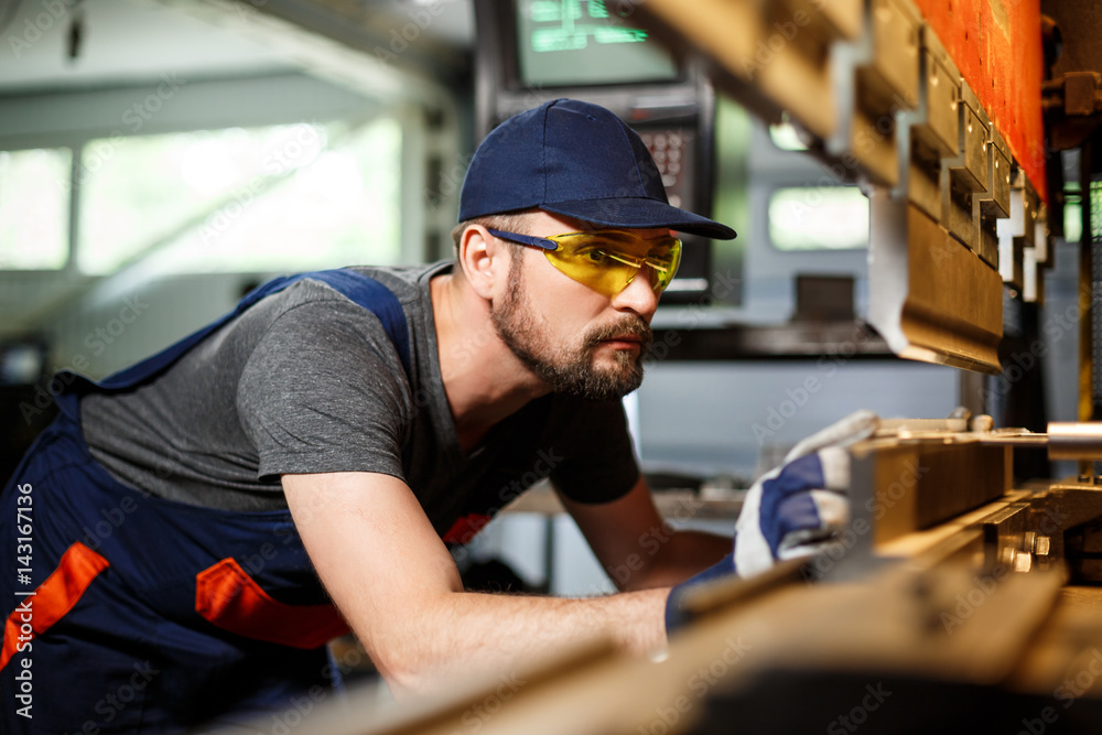 Portrait of worker near metalworking machine, steel factory background. Portrait of worker near metalworking machine, steel factory background.
