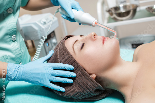 Face Beauty Treatment. Beautician makes Facial Darsonval Therapy for woman 