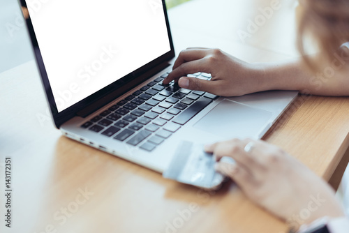Asian Woman holding credit card and typing keyboard on blank screen laptop with shopping online in selective focus.
