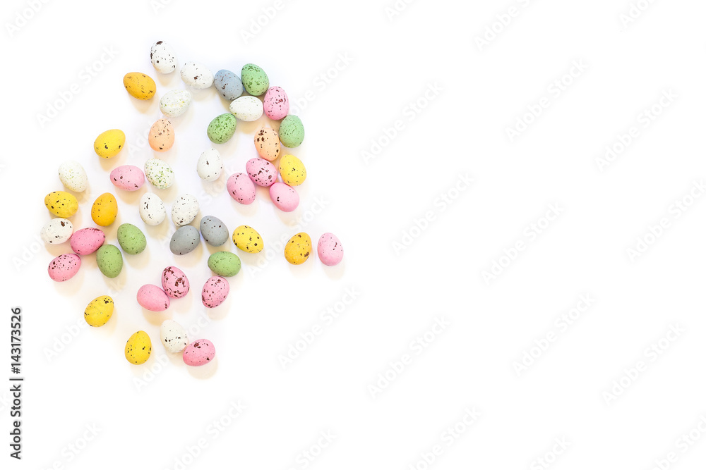 Spilled multicolored quail eggs or small painted chocolate eggs on a white background.