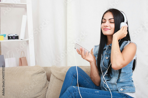 One relaxed girl resting and listening music with headphones sitting on sofa photo