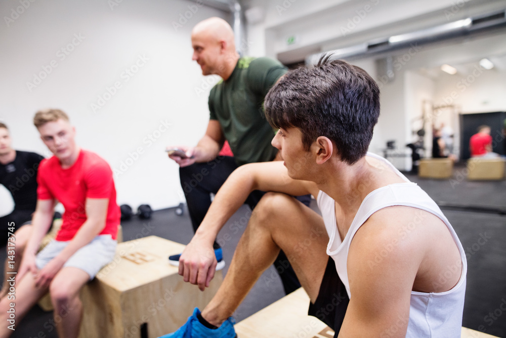 Men in gym resting after exercising on fit boxes. Men in gym resting after exercising on fit boxes.