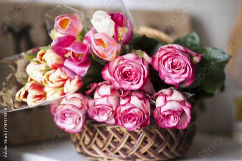 Pink roses and colored tulips are in the basket