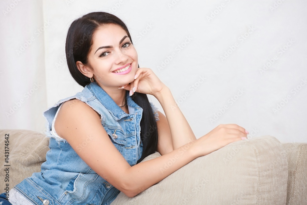 Relaxed casual brunette in blue cardigan and In blue jeans sits on the couch Relaxed casual brunette in blue cardigan and In blue jeans sits on the couch
