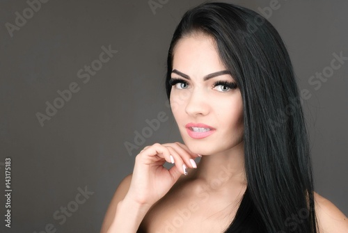 Young and beautiful woman with long brown hair posing over grey background