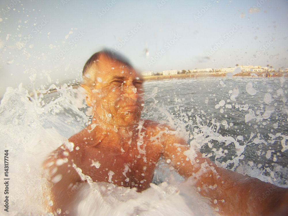 Obraz premium Man makes self in the sea when a wave hits him in the face