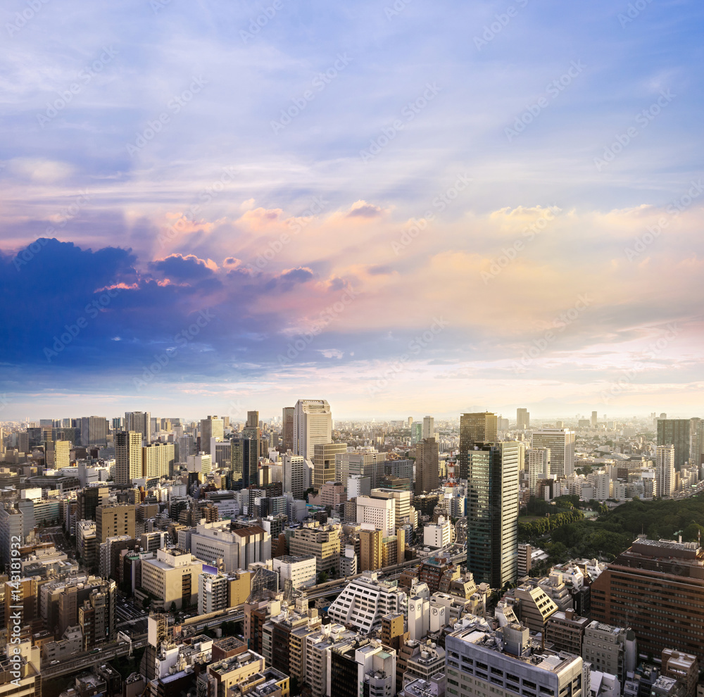 Fototapeta premium Cityscape of Tokyo, city aerial skyscraper view of office building and downtown and street of minato in tokyo with sunset / sun rise background with light beam pass cloud, tokyo. Japan, Asia