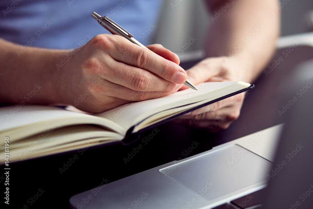 Close up of man writing on paper notebook with pen Close up of man writing on paper notebook with pen