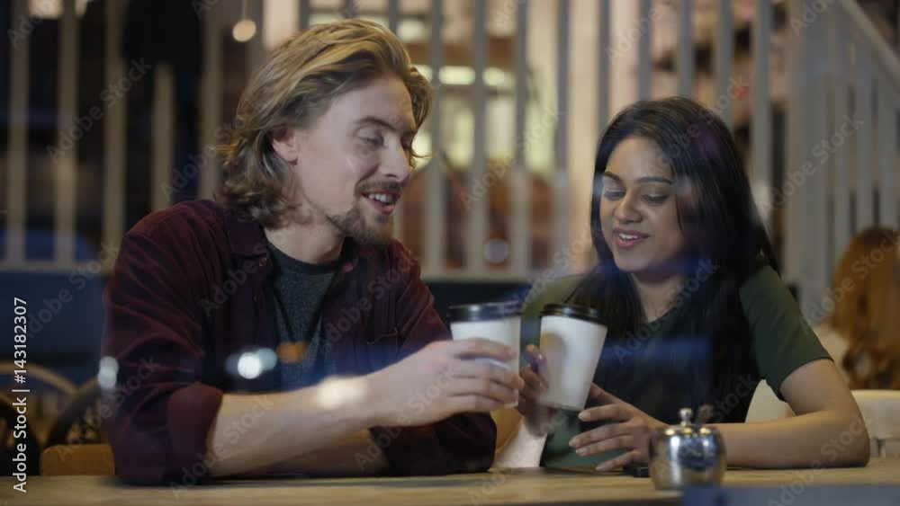 Happy young couple chatting & having drinks in city coffee shop Happy young couple chatting & having drinks in city coffee shop