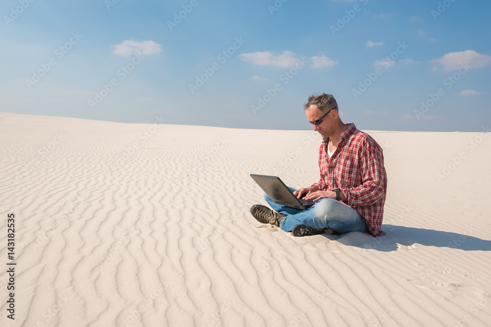 Concerned man with a laptop sits in desert