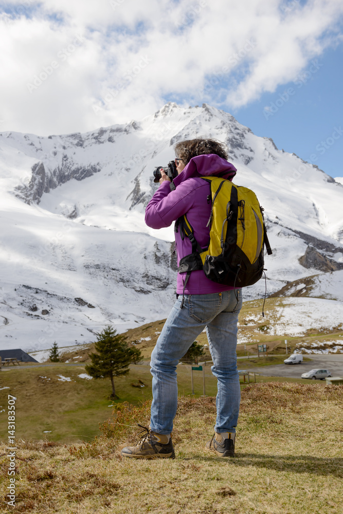 Hiker with camera and backpack taking picture of beautiful mountain