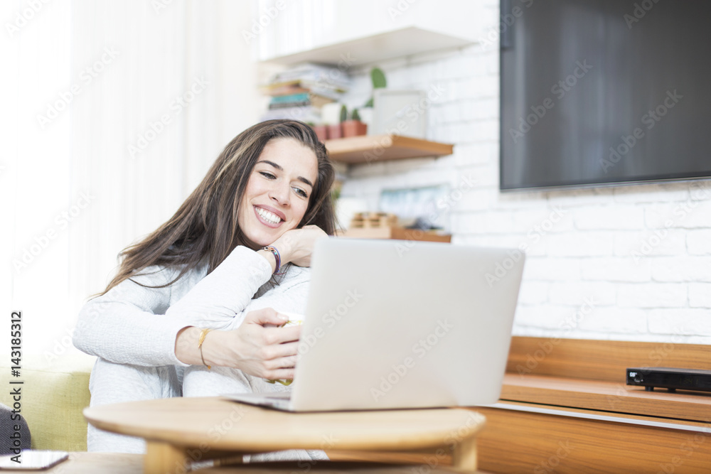 Young beautiful woman sitting on the floor working on laptop. Morning scene