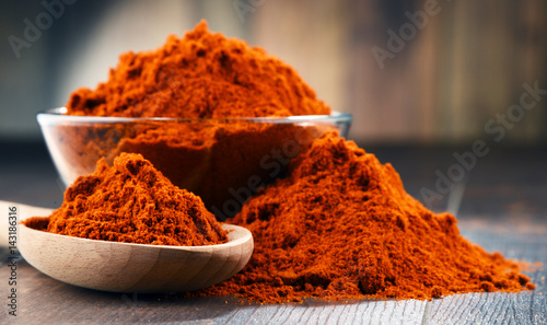 Composition with bowl of chili powder on wooden table