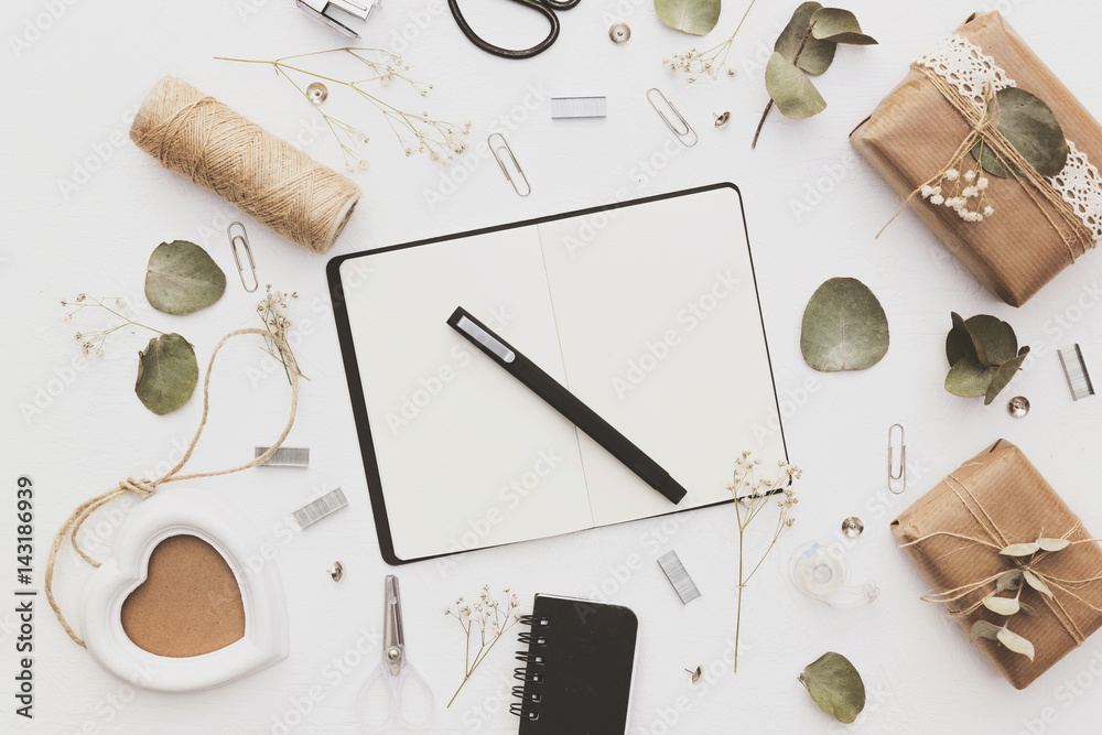 Feminine workspace with notebook, paper blank, decorative branch, pencils. Business concept. Flat lay, top view Feminine workspace with notebook, paper blank, decorative branch, pencils. Business concept. Flat lay, top view