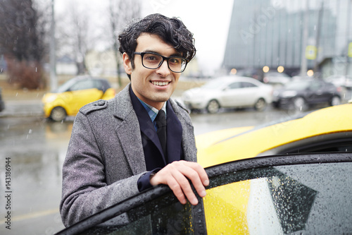 Tablou pe pânză Portrait of young handsome  Middle-Eastern businessman getting in  taxi cab on r