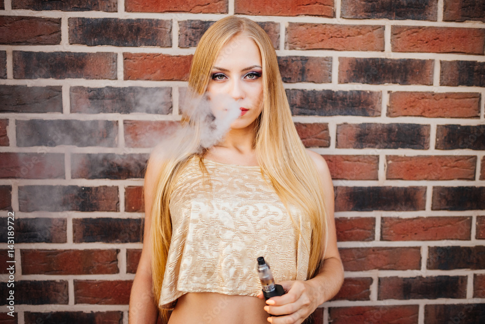 Sexy girl smokes electronic cigarette. The model vaper vaping a vaporizer. Vaping.