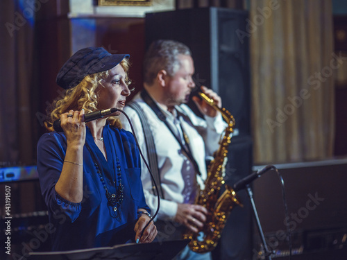 A singer and saxophonist in a restaurant. Artists of European appearance appear on stage.