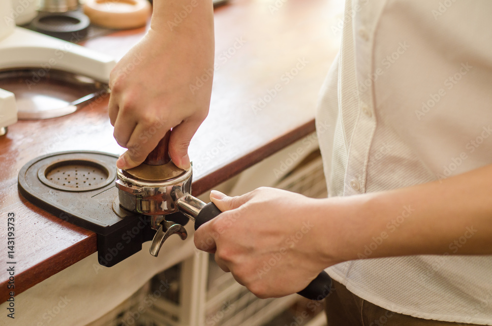 Close up of barista tamping fresh coffee for making espresso. Close up of barista tamping fresh coffee for making espresso.