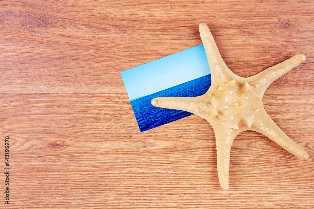 Top view of traveller's objects: photo card of the sea and sea star Top view of traveller's objects: photo card of the sea and sea star
