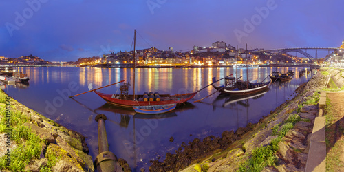 Panoramic view  traditional rabelo boats with barrels of Port wine on the Douro river  Ribeira and Dom Luis I or Luiz I iron bridge on the background  Porto  Portugal.