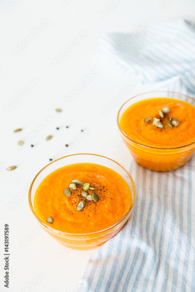 Two plates of pumpkin soup with seeds on a white background with space for your text. Two plates of pumpkin soup with seeds on a white background with space for your text.