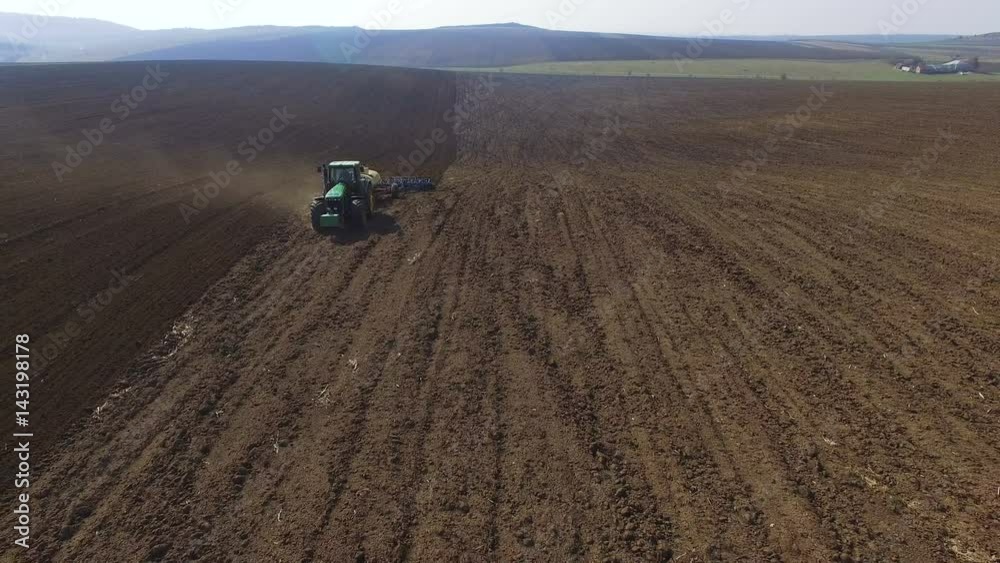 Aerial view of a tractor cultivating a fields with black soil for planting in 4K Aerial view of a tractor cultivating a fields with black soil for planting in 4K