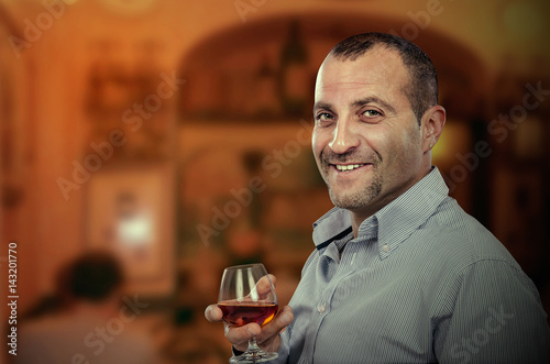 Cheerful middle-aged man posing with glass of brandy