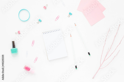 Colorful workspace with polish, pink and turquoise woman's accessories, notebook and pencil on white background. Flat lay, mock up, top view