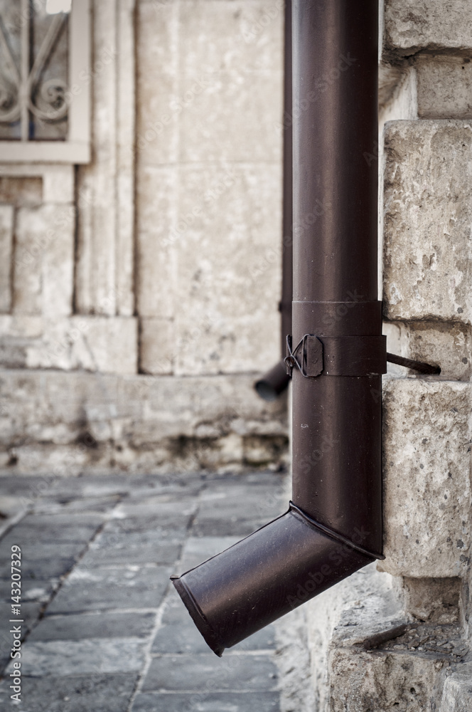 metal drainpipe on the corner of a stone house metal drainpipe on the corner of a stone house