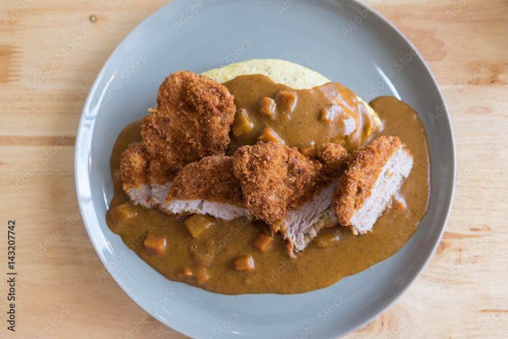 Omelette Rice with Japanese Curry and Breaded Deep Fried Pork Cutlet on Modern Wood Table Omelette Rice with Japanese Curry and Breaded Deep Fried Pork Cutlet on Modern Wood Table