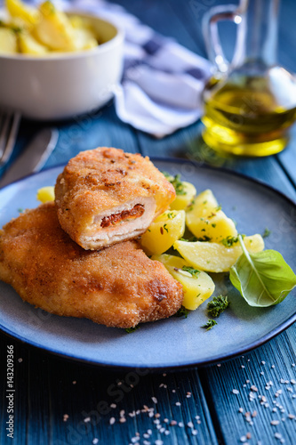 Fried pork cutlets stuffed with sun - dried tomato and Roquefort cheese, served with potato