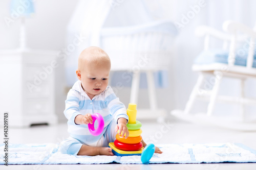 Baby playing with toy pyramid. Kids play