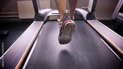 Back view of female legs walking and running on treadmill in gym, woman training