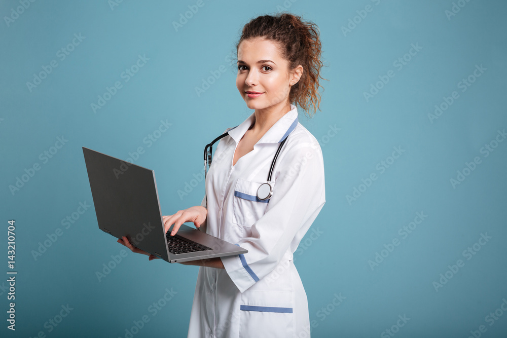 Smiling female doctor holding laptop