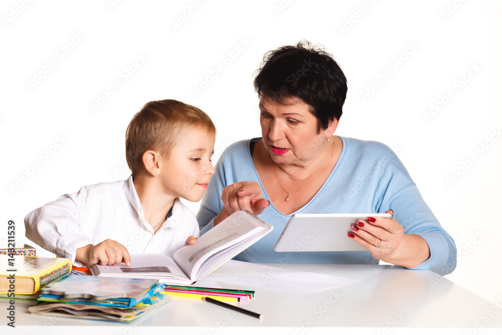 Grandmother with grandson learn and draw at table on a white background Grandmother with grandson learn and draw at table on a white background